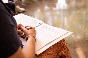 Photo of a person's lap with a pen and notebook